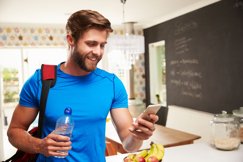 41146850 - man wearing gym clothing looking at mobile phone